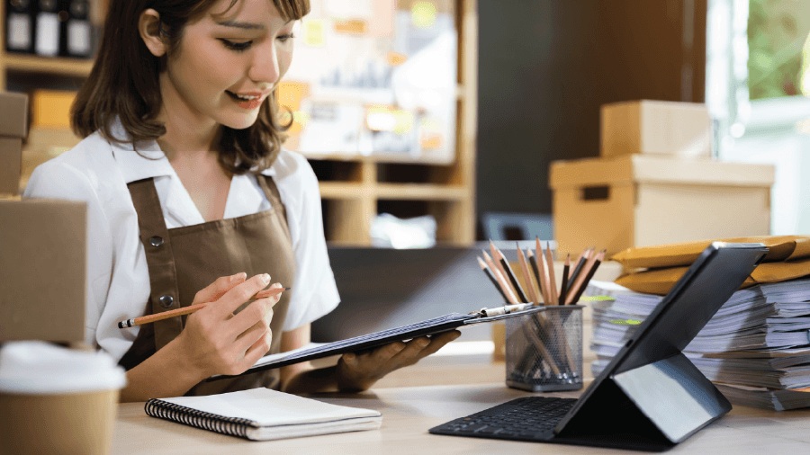 Recommended retail management system eRunlite, showing a store manager checking invoices on a clipboard and using a tablet, featuring custom receipts and quotation-to-sales order conversion.